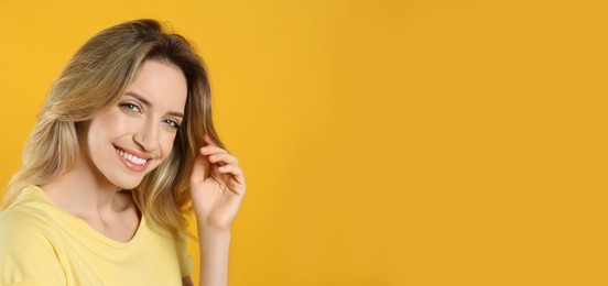 Photo of Portrait of happy young woman with beautiful blonde hair and charming smile on yellow background. Space for text