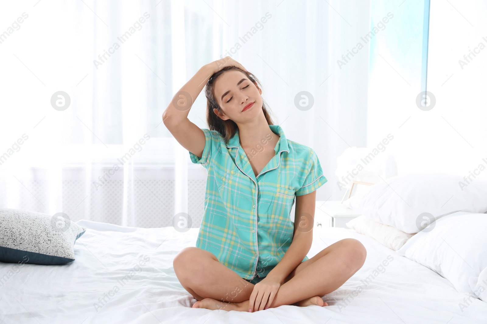 Photo of Young woman practicing yoga on bed at home. Morning fitness