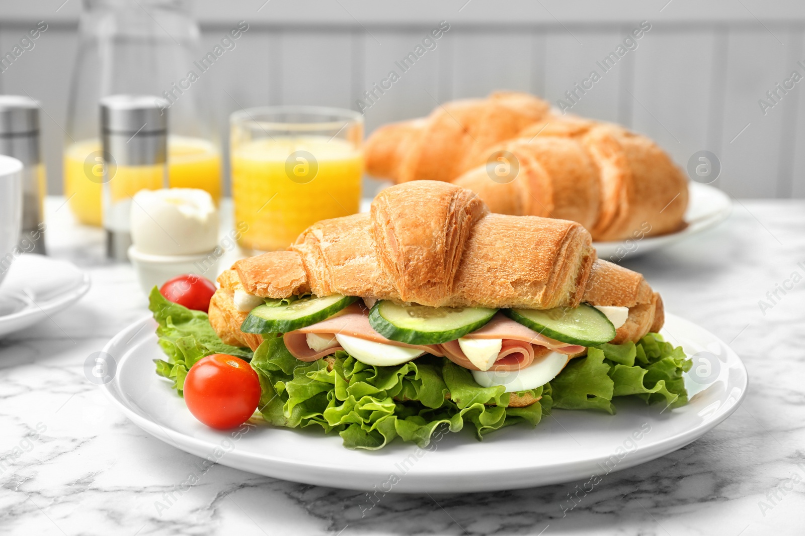 Photo of Tasty croissant sandwich with sausage on table