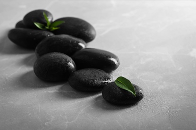 Photo of Spa stones with water drops and green leaves on light table