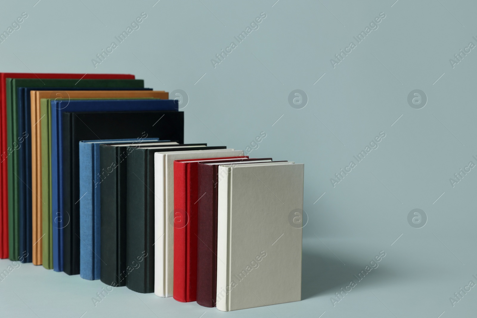 Photo of Many different hardcover books on light grey background. Space for text