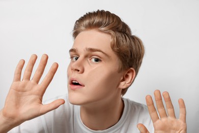 Shocked teenage boy stuck to transparent screen