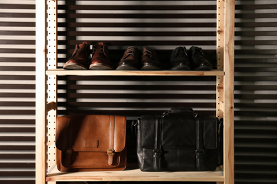 Photo of Wooden shelving unit with different leather shoes and bags