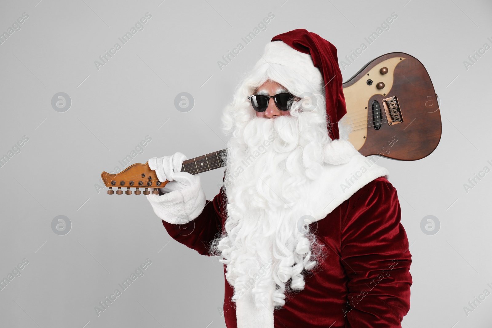 Photo of Santa Claus with electric guitar on light grey background. Christmas music