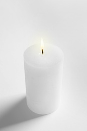 Photo of Pillar wax candle burning on white background