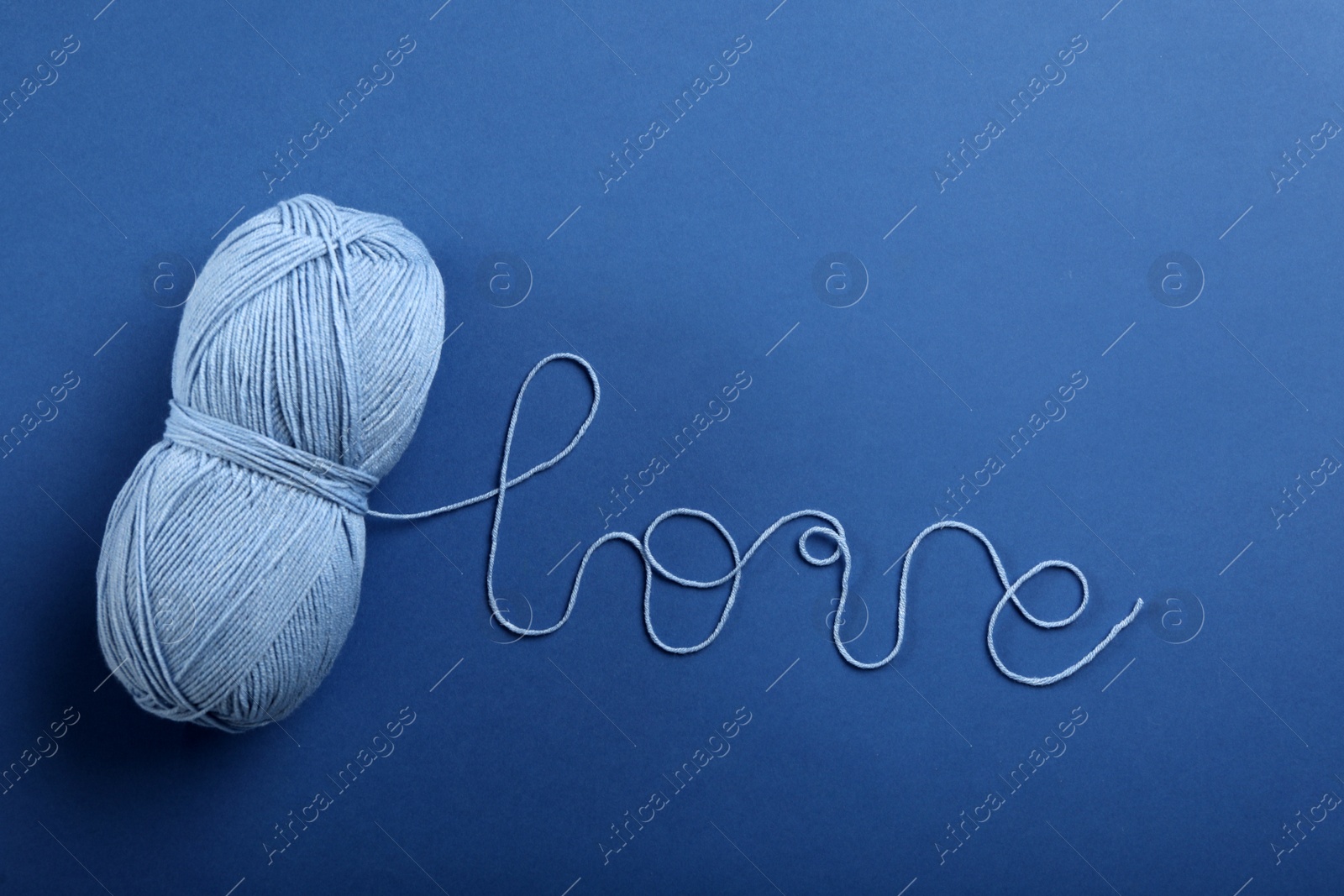 Photo of Word Love made with thread and woolen yarn on blue background, top view