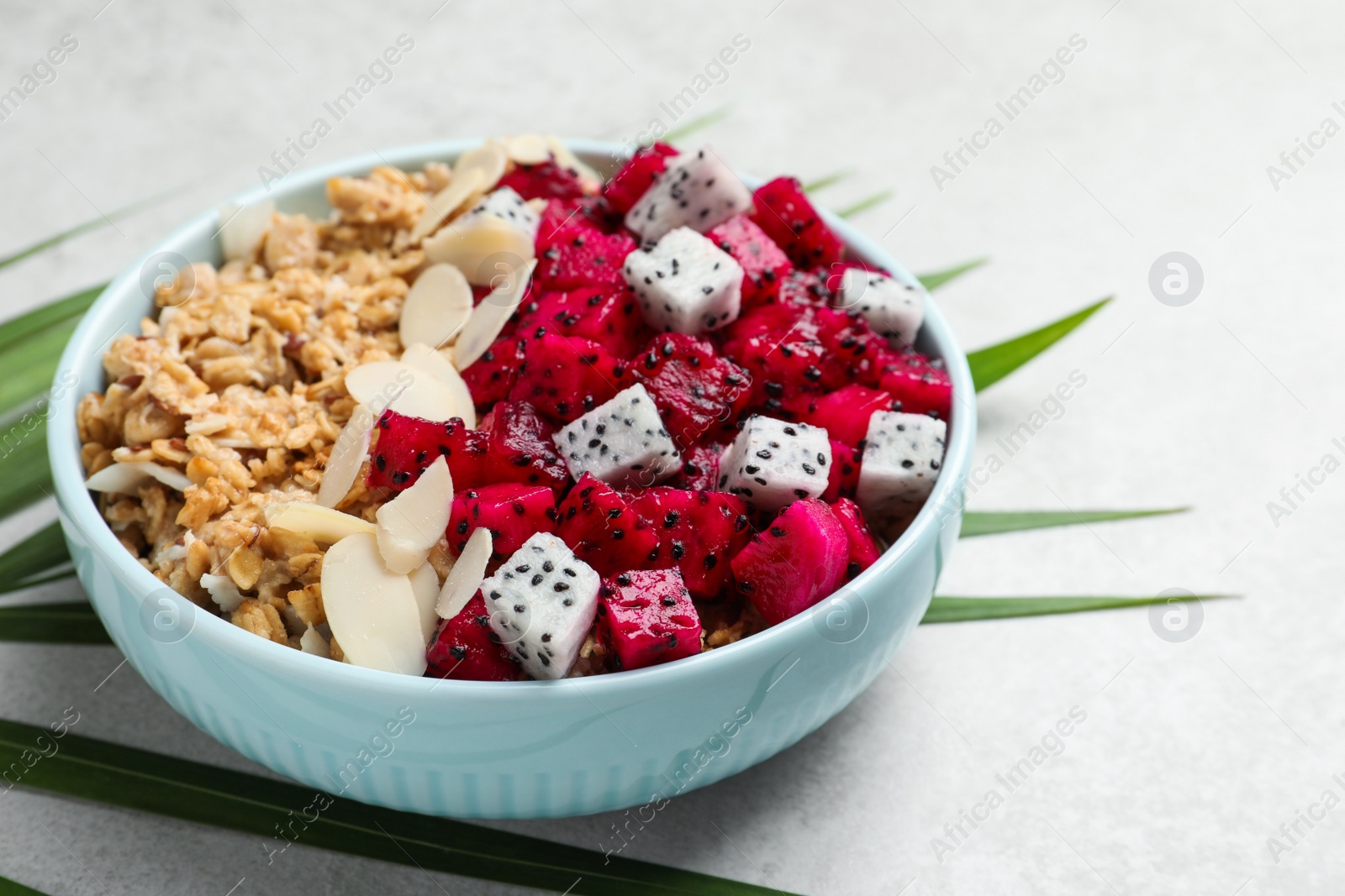 Photo of Bowl of granola with pitahaya and almond petals on light table