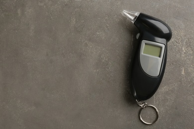 Photo of Modern breathalyzer with blank screen on grey stone table, top view. Space for text