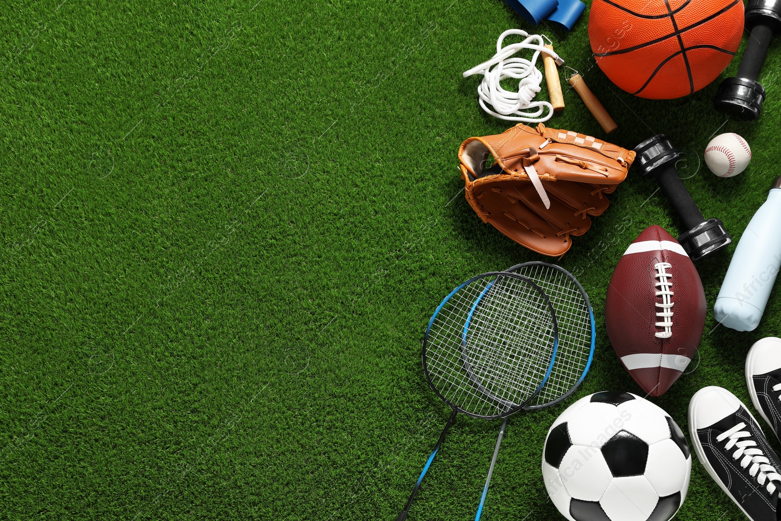 Photo of Different sports equipment on green grass, flat lay. Space for text