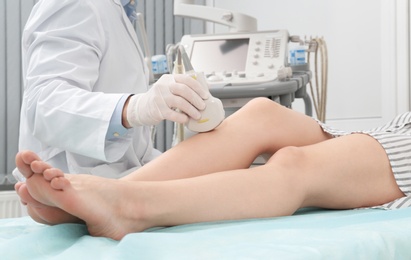 Doctor conducting ultrasound examination of patient's knee in clinic, closeup