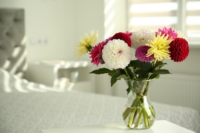 Photo of Bouquet of beautiful Dahlia flowers in vase on white table indoors. Space for text