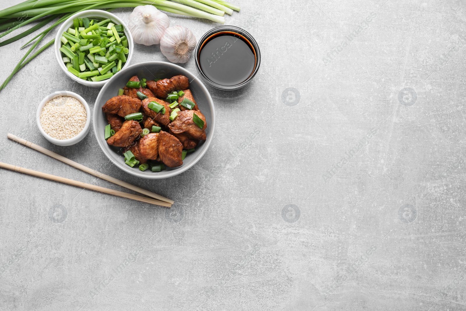 Photo of Tasty soy sauce, roasted meat and ingredients on grey table, flat lay. Space for text