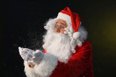 Photo of Merry Christmas. Santa Claus blowing snow on dark background