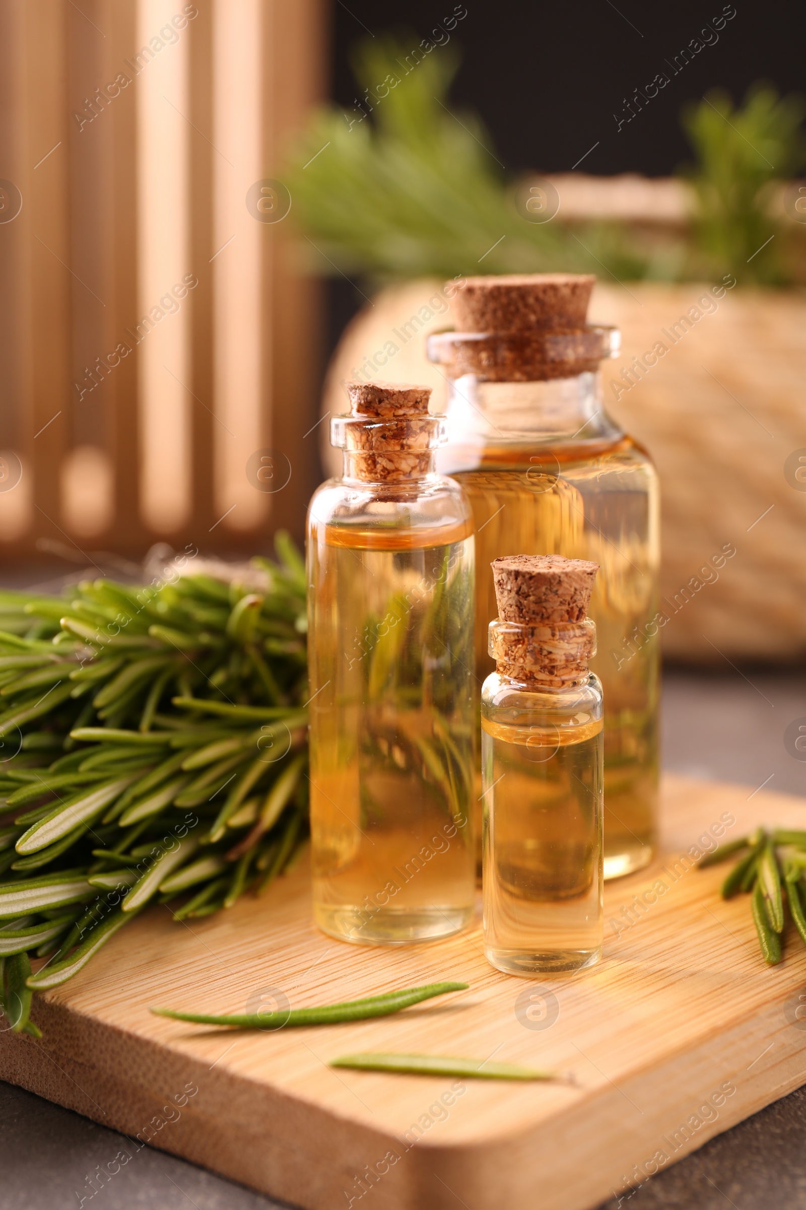 Photo of Essential oil in bottles and rosemary on table