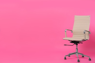 Comfortable office chair on pink background, space for text