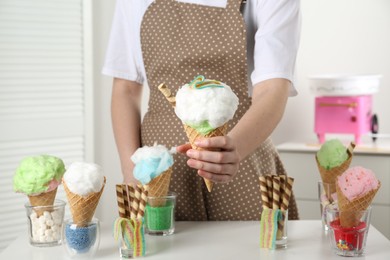 Woman holding waffle cone with cotton candy indoors, closeup