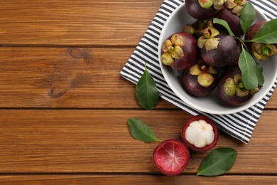 Photo of Fresh ripe mangosteen fruits on wooden table, flat lay. Space for text