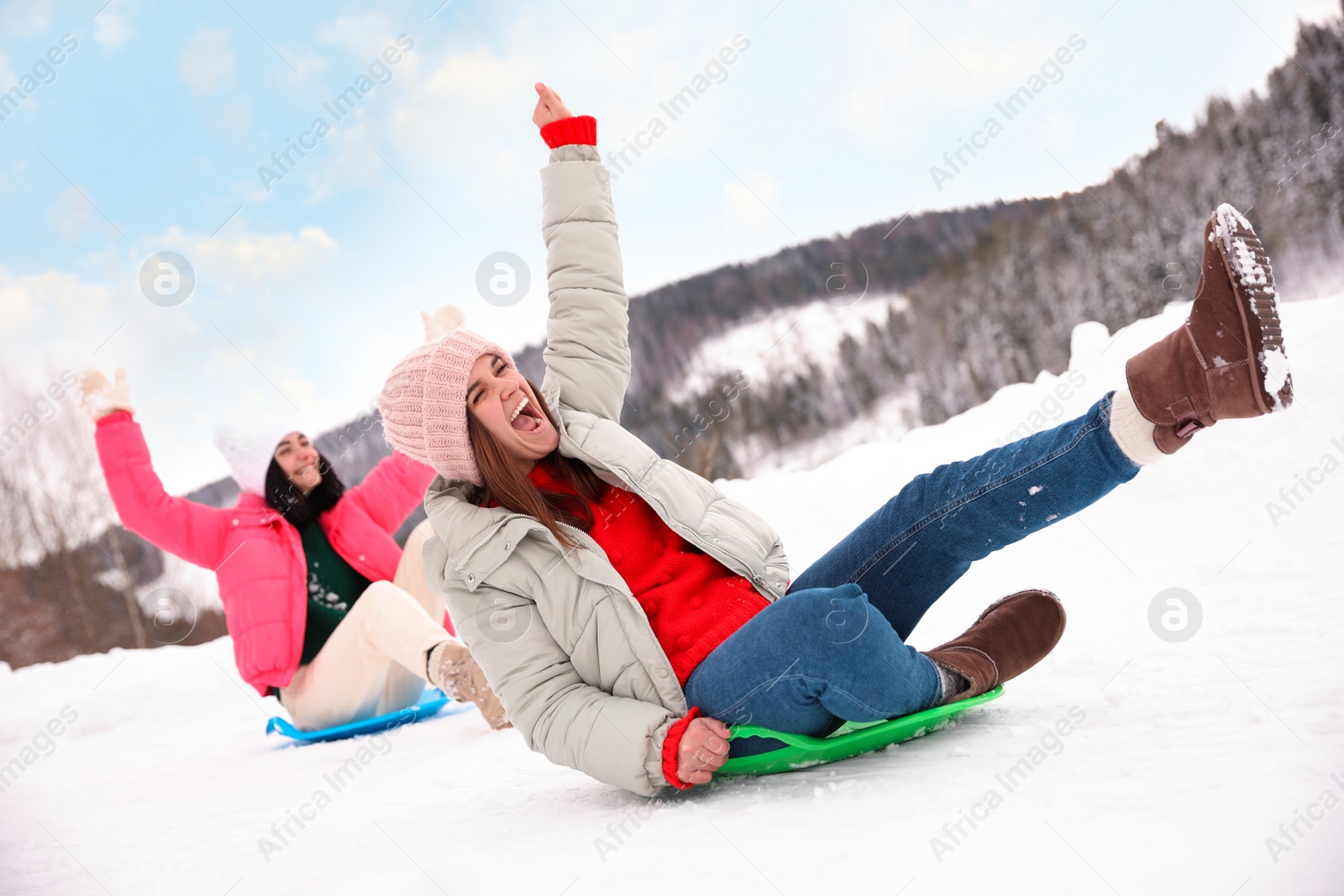 Photo of Happy friends having fun and sledding on snow. Winter vacation