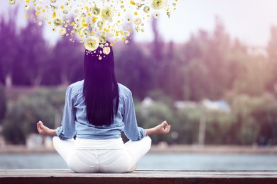 Woman meditating near river, back view. Flowers near her head symbolizing state of mindfulness