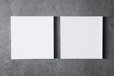 Blank paper sheets on grey textured background, top view. Mockup for design