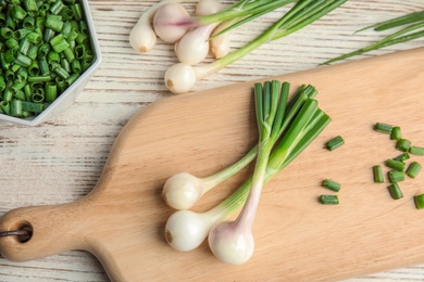 Photo of Wooden board with fresh green onion on table, top view