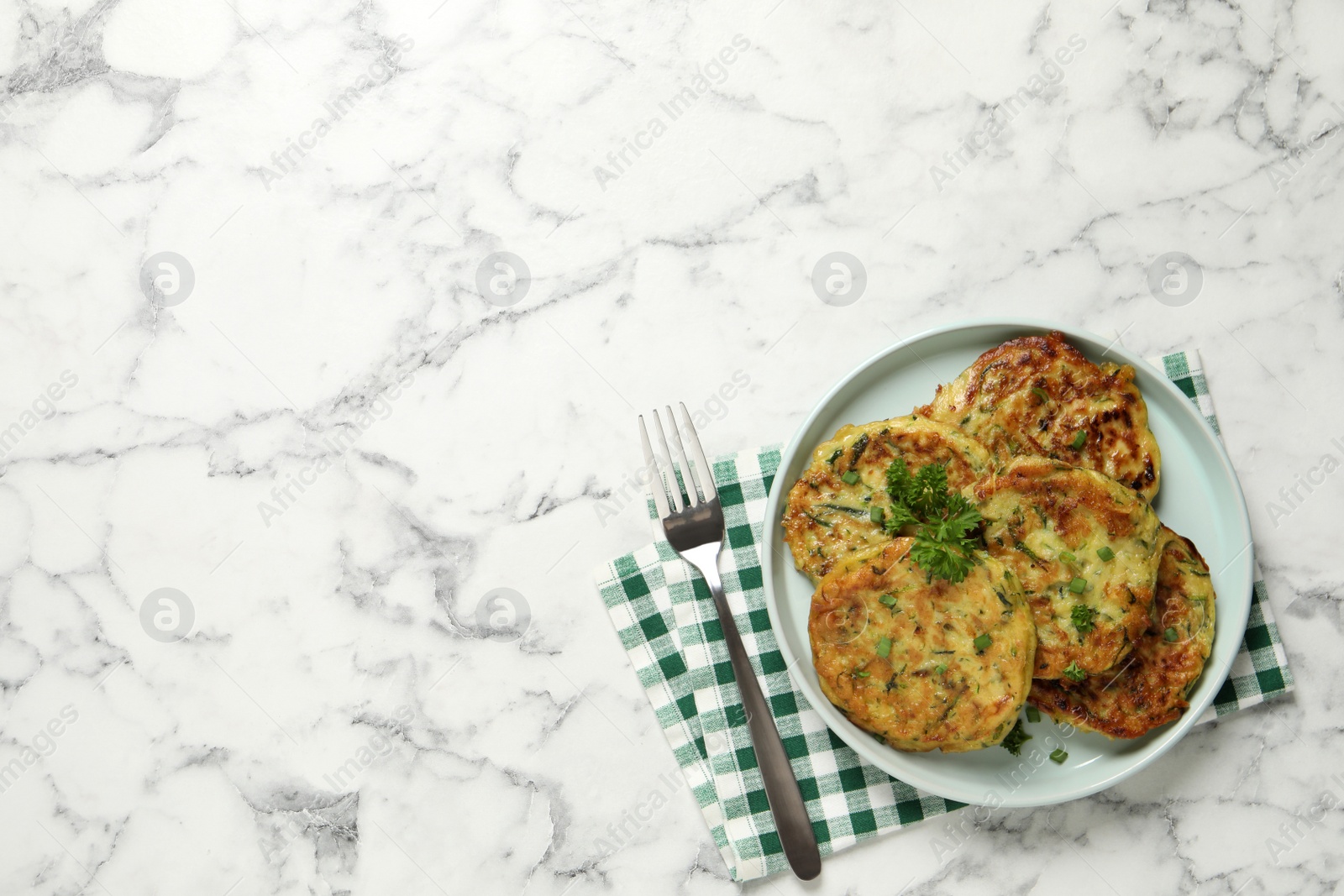 Photo of Delicious zucchini fritters served on white marble table, flat lay. Space for text