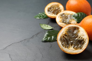 Delicious ripe granadillas and leaves on black table. Space for text