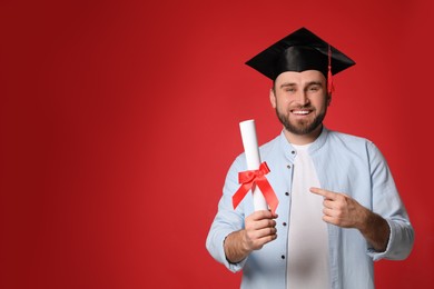 Happy student with graduation hat and diploma on red background. Space for text