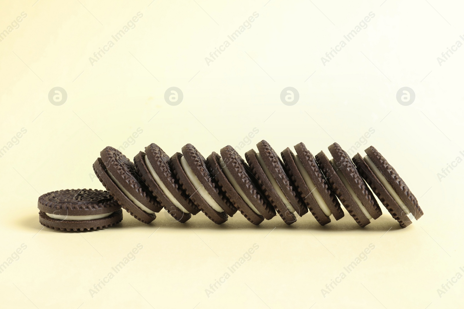 Photo of Tasty chocolate cookies with cream on color background. Space for text