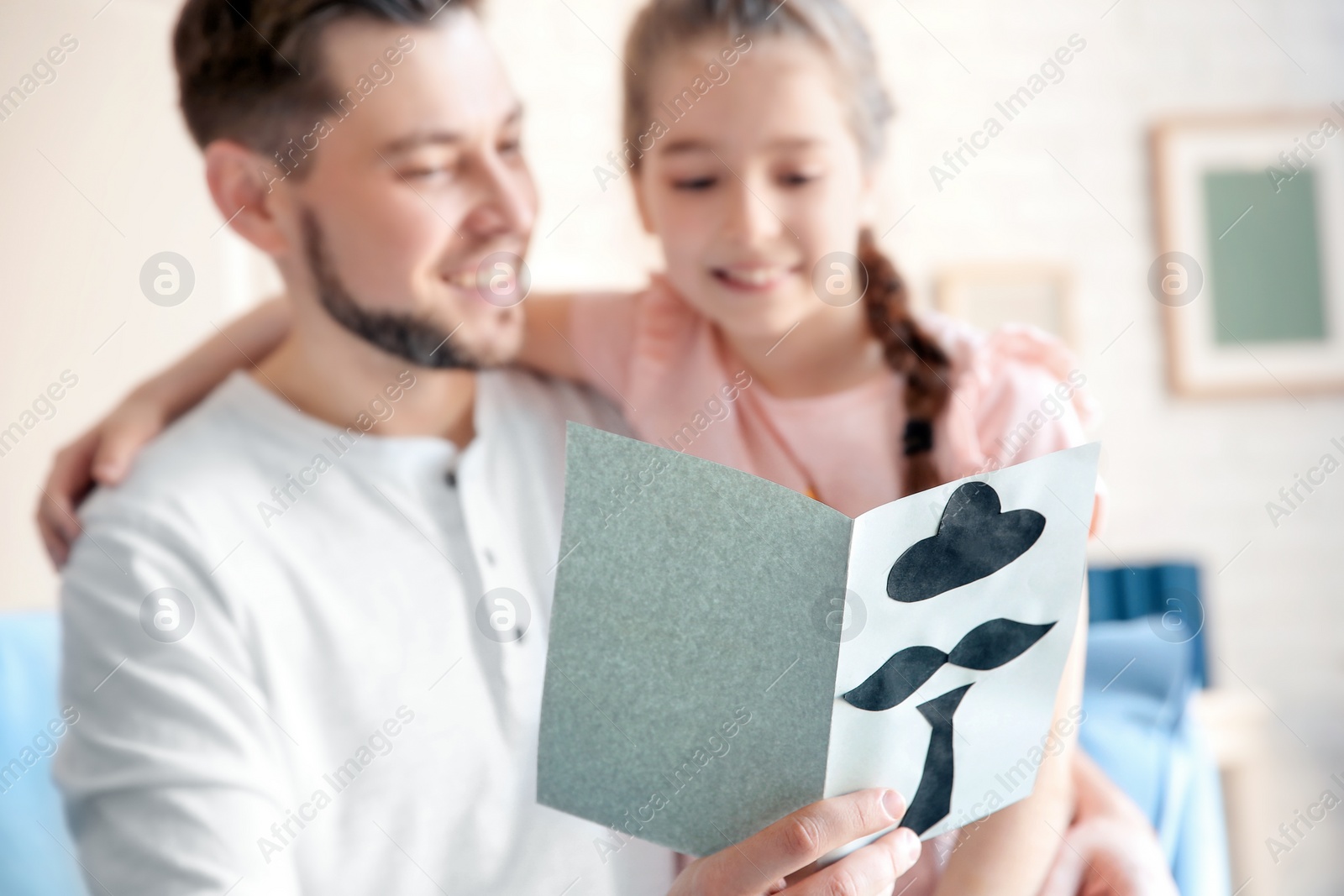 Photo of Little girl greeting her dad with Father's Day at home