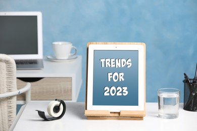 Trends For 2023 text on tablet display. Stationery and device on wooden table