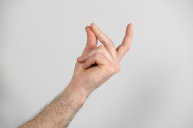 Photo of Man snapping his fingers on light grey background, closeup. Bad habit