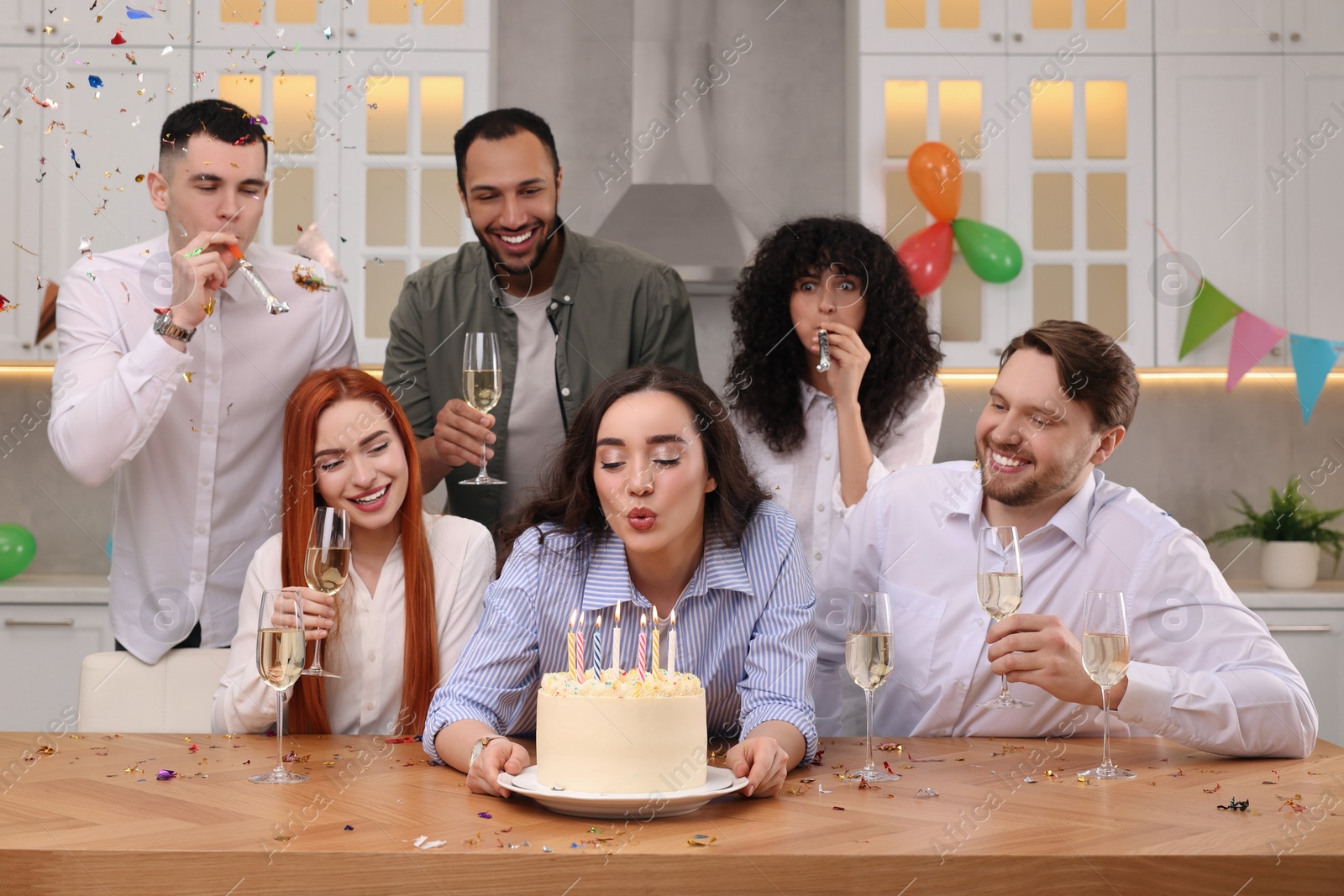 Photo of Happy friends with tasty cake celebrating birthday in kitchen