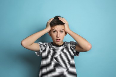 Worried teenage boy on light blue background