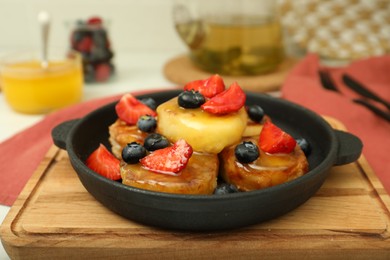 Photo of Delicious cottage cheese pancakes with fresh berries and honey served on table, closeup