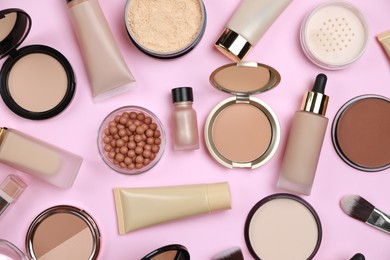 Face powders and other decorative cosmetic products on pink background, flat lay