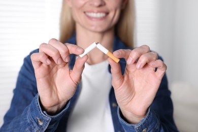 Photo of Woman breaking cigarette on light background, selective focus. Quitting smoking concept