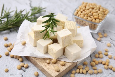 Photo of Delicious tofu cheese, rosemary and soybeans on light gray textured table, closeup