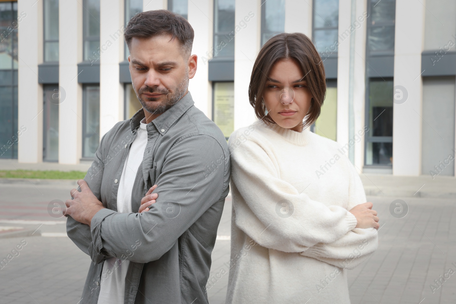 Photo of Unhappy man and woman standing near each other outdoors. Relationship problems