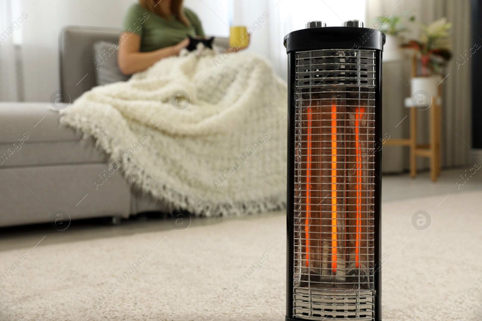 Photo of Woman with cat at home, focus on electric halogen heater, closeup