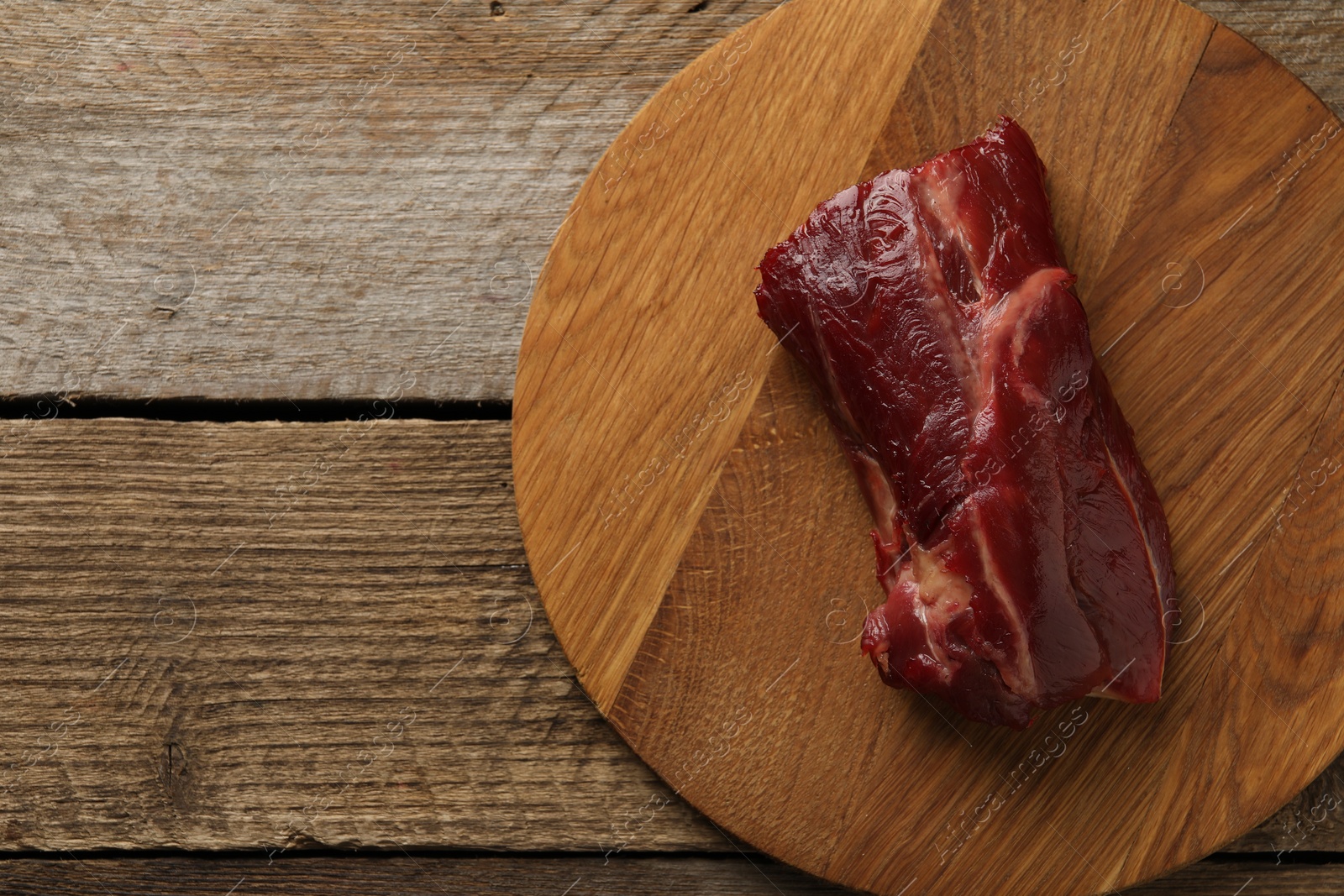 Photo of Piece of raw beef meat on wooden table, top view. Space for text