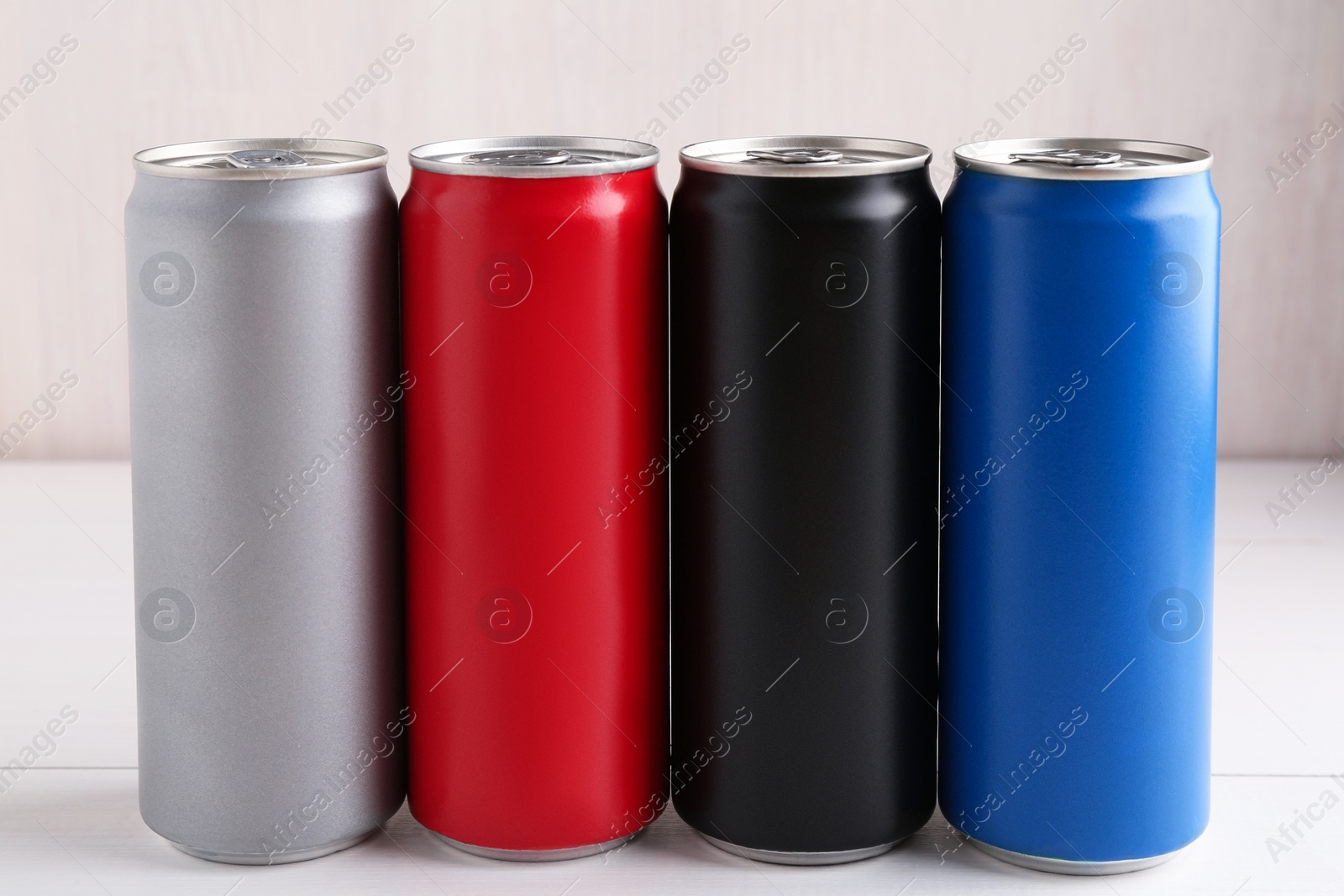 Photo of Energy drinks in colorful cans on white wooden table