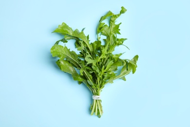 Fresh arugula on light blue background, top view