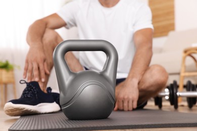Man with kettlebell on floor at home, closeup