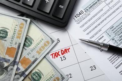 Photo of Calendar with date reminder about tax day, documents, money, pen and calculator, top view