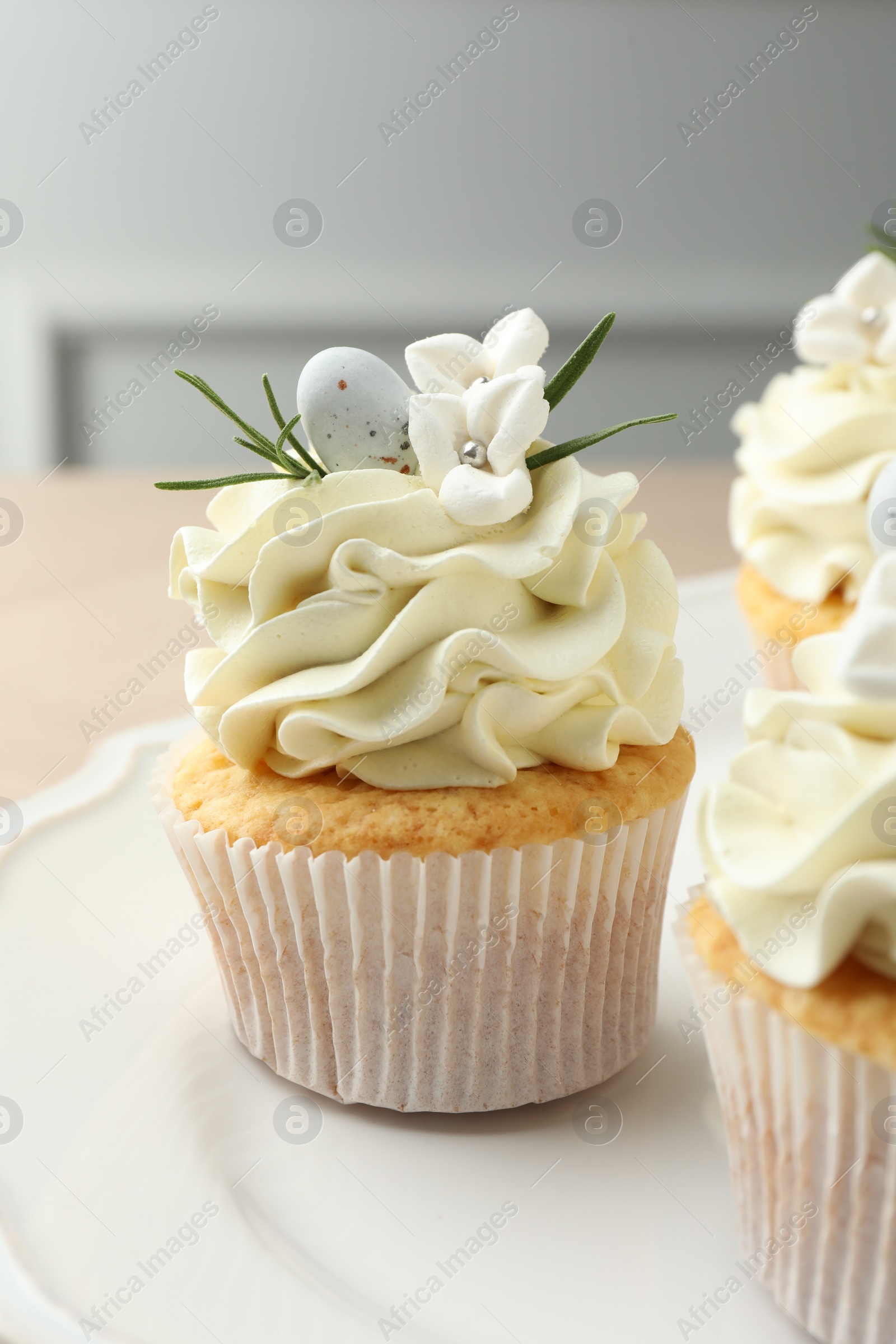 Photo of Tasty Easter cupcakes with vanilla cream on table, closeup