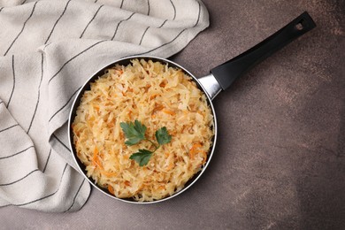 Frying pan with sauerkraut on brown table, top view