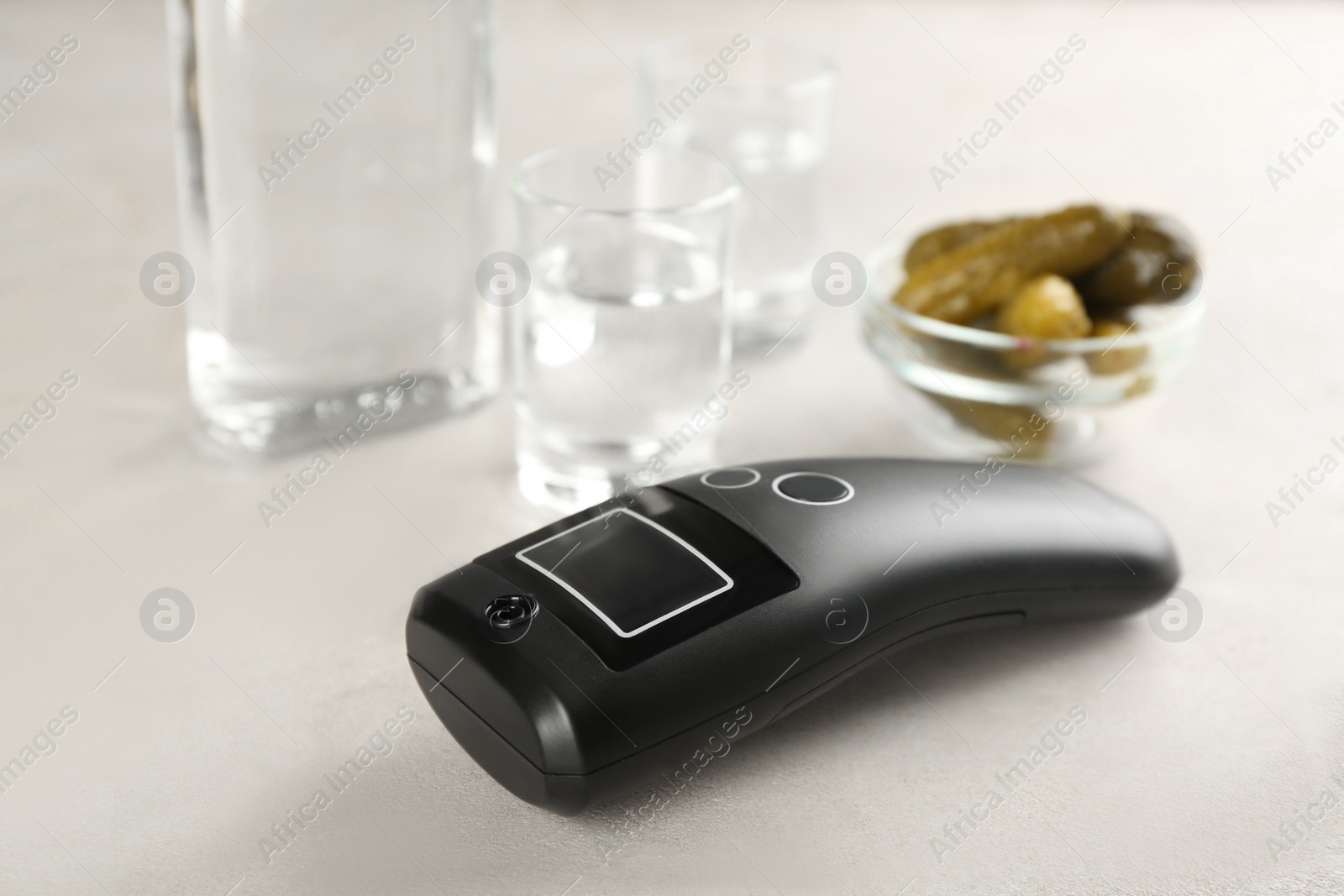 Photo of Modern breathalyzer and vodka on white table