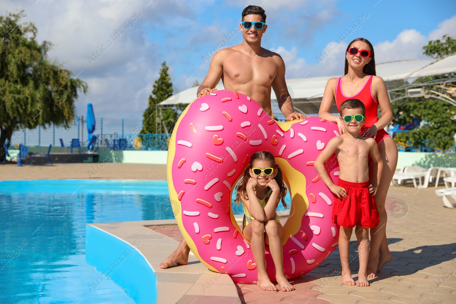 Photo of Happy family with inflatable ring near swimming pool.  Summer vacation