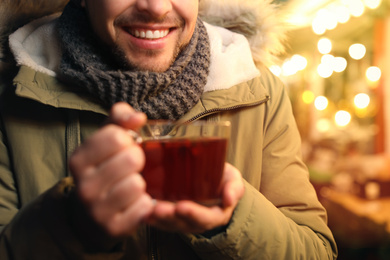 Photo of Happy man with mulled wine at winter fair, closeup